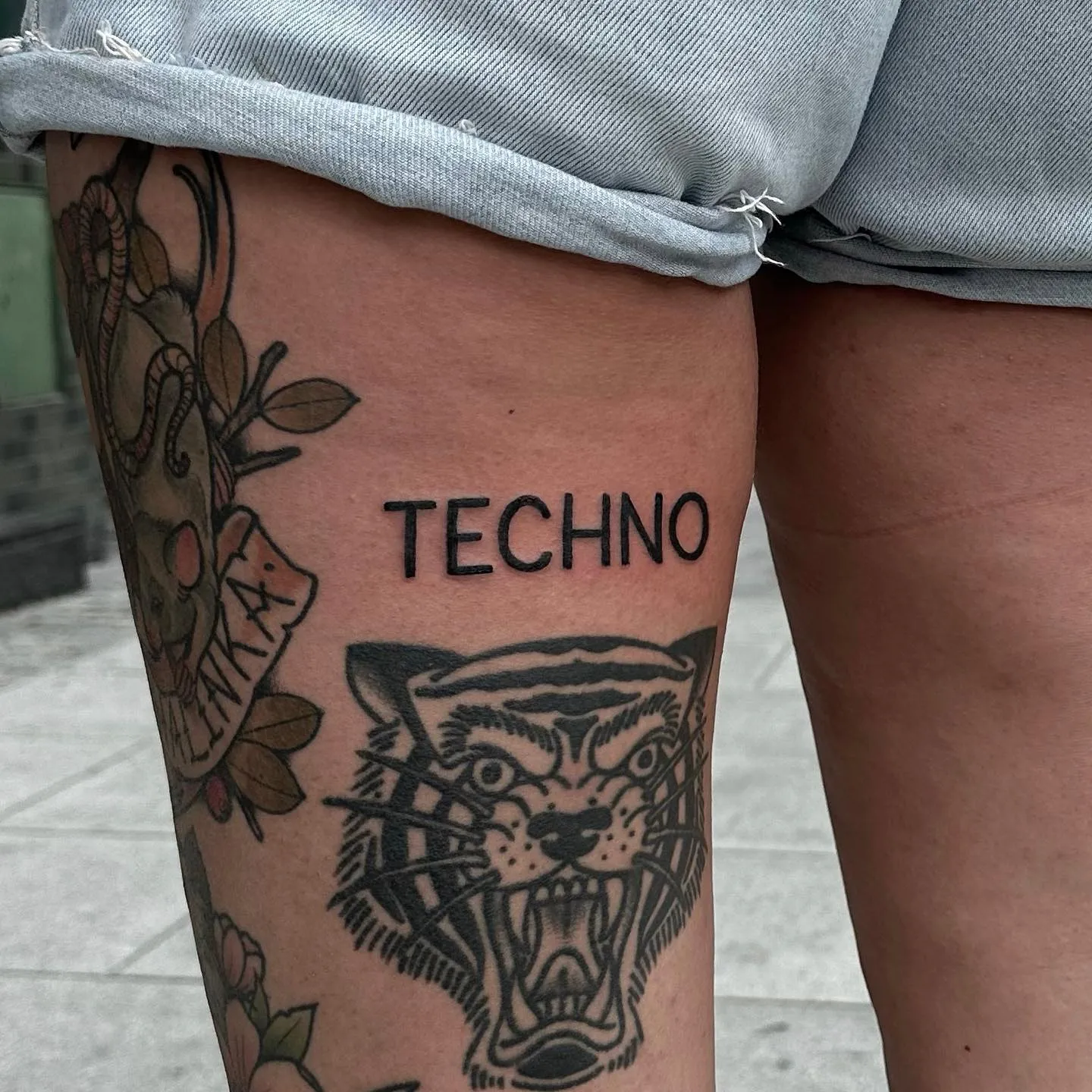 Tatuaż z tygrysem i napisem TECHNO w grubym konturze — tatuaż, Wujek Darek, Warszawa, Polska