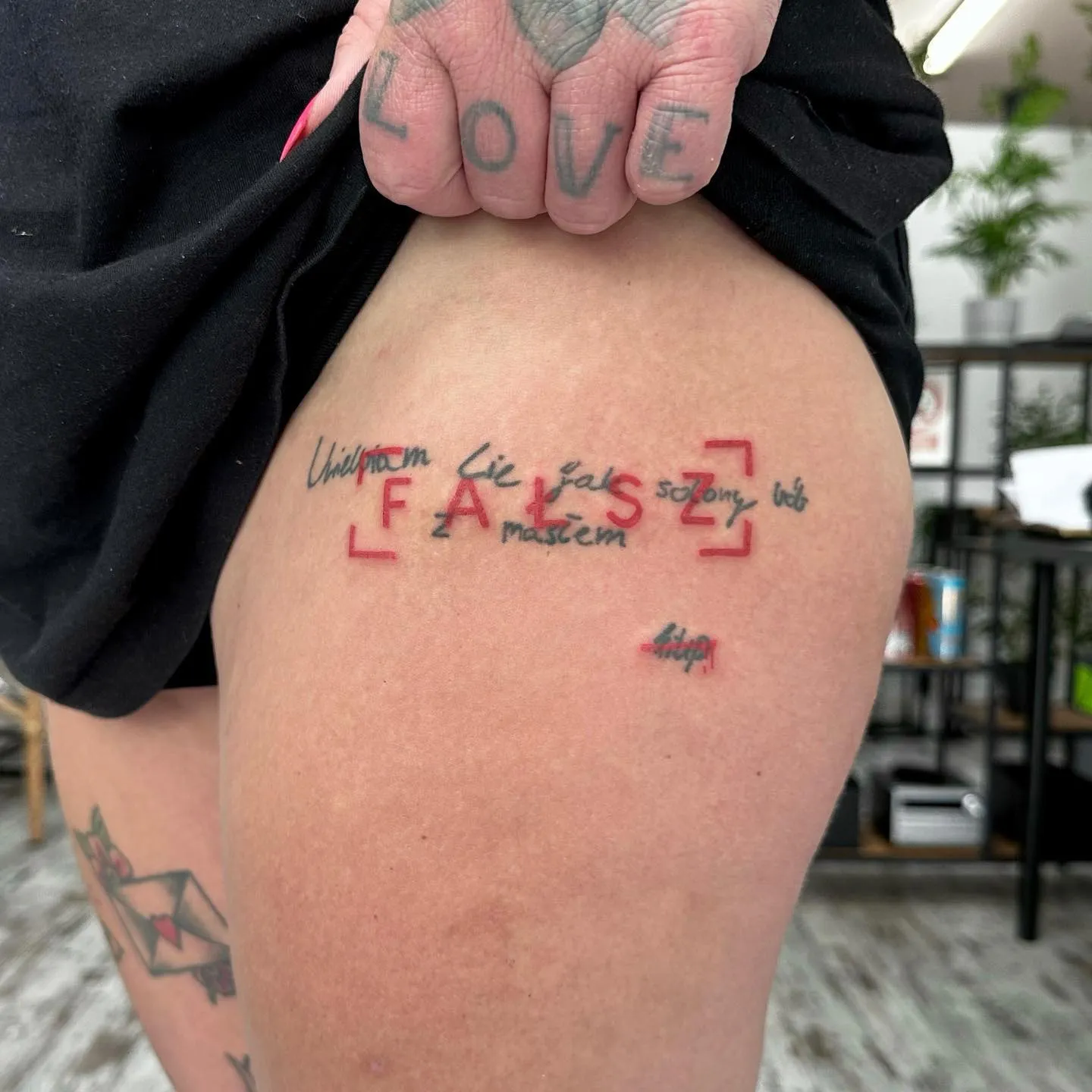 Tatuaż z napisem FALSE w ultragrubym konturze i czerwonymi nawiasami — tatuaż, Wujek Darek, Warszawa, Polska