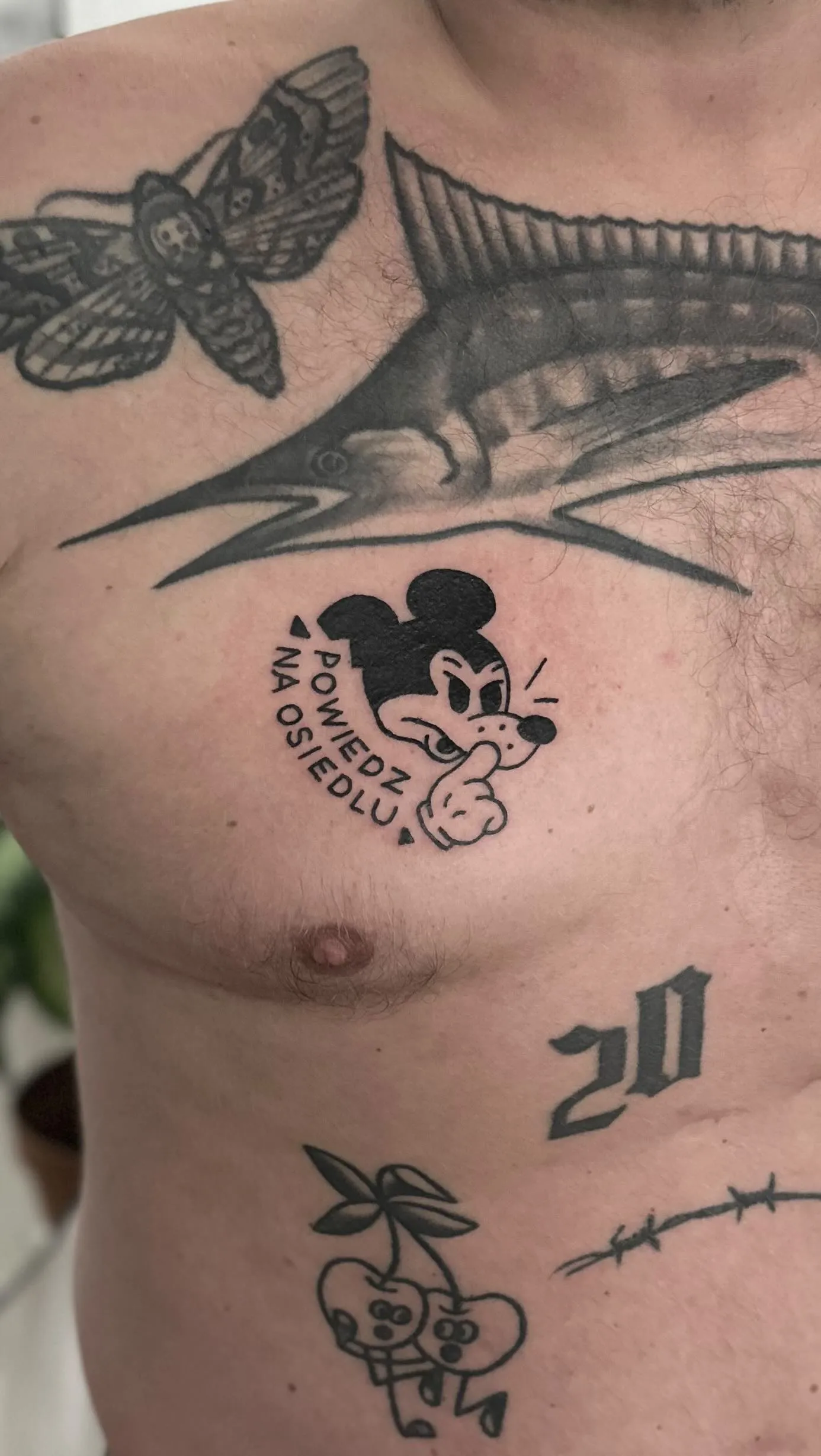 Ignorant tatuaż wściekłego Myszki Mickey z napisem w łuku na klatce piersiowej — tatuaż, Wujek Darek, Warszawa, Polska