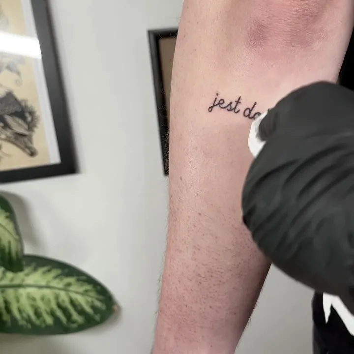 Lettering tatuaż na przedramieniu z cienkimi liniami — tatuaż, Wujek Darek, Warszawa, Polska